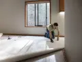 Un hombre instala una moqueta nueva en una habitación vacía. La moqueta es de color crema y se desenrolla por el suelo.