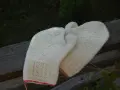 Två par vantar i naturvit ull, stickade med tvåändsstickning och fina mönster. De har en röd kant nertill.