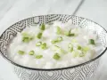 Miseczka ryżowej owsianki z zieloną cebulką. Idealne danie, gdy zastanawiasz się, co jeść na ból brzucha.