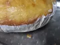 Goldbrauner Teig klebt am Backpapier, das auf einem Metallblech liegt. Ein Teil des Teigs ist bereits abgelöst.