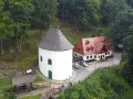 Miłków atrakcje: biała wieża z krzyżem i czerwony budynek z dachówką, otoczone zielonym lasem.