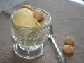 Ein Glas mit cremigem Marzipan Eis, garniert mit kleinen Keksen. Daneben liegen zwei weitere Kekse und ein Löffel.