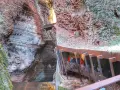 Un orrido ponte alto attraversa una gola rocciosa, con persone che salgono una scalinata metallica.