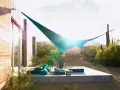 Terraza moderna con toldos vegetales que protegen del sol del desierto. Muebles cómodos y cactus al fondo.