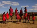 Kenia: ludzie z plemienia Masajów skaczą w rytm tradycyjnej pieśni, ubrani w czerwone stroje.