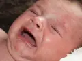 Zanoszenie się dziecka, z zamkniętymi oczami i otwartymi ustami, wyraża swoje emocje.