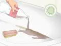 Aplicando líquido de una botella para quitar el óxido de la bañera, junto a un cepillo.