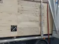Drewniana skrzynia z widocznym fragmentem felgi, gotowa do transportu. Widać logo firmy transportowej i oznaczenia towaru.