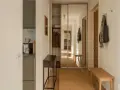 En snygg hall med en spegelgarderob, en smal konsol, en träbänk och en matta. En jacka och en väska hänger på krokar.