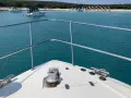 Bugspitze mit Ankerwinde und Leinen, bereit zu zeigen, wie ankert man richtig. Im Hintergrund eine Bucht mit Booten und Strand.