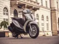 Biały skuter Piaggio Medley zaparkowany na bruku przed zabytkową kamienicą.