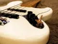 Ein weißes Bassmusikinstrument mit vier Saiten und einem bronzenen Kreisel auf dem Bedienfeld.