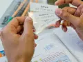 Hände halten Lernkarten zum Fremdsprachen lernen. Vokabeln wie "Schrank" und "Handtücher" werden geübt.