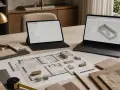 Na stole leży plan mieszkania, próbki materiałów i dwa laptopy z otwartą aplikacją do projektowania wnętrz.