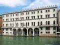 Palazzo sul Canal Grande, un tempo sede dei mercanti tedeschi, con le sue arcate e finestre che riflettono l'acqua di Venezia.