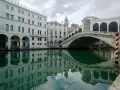 Le vie di Venezia, con il Ponte di Rialto che si specchia sull'acqua verde e gli edifici storici che creano un'atmosfera magica.