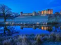 Un château majestueux se reflète dans l'eau calme, sous un ciel d'un bleu profond. Une scène paisible de **heure bleue photo**.