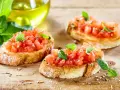Bruschetta z pomidorami i mozzarellą – pyszny przepis na letnią przekąskę. Chrupiące grzanki z soczystymi pomidorami i świeżą bazylią.