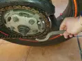 Mano con chiave speciale per regolare la catena della moto, mostrando come tirare la catena.