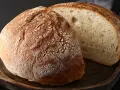 Chleb na kefirze, z chrupiącą skórką i puszystym wnętrzem, prezentuje się apetycznie na drewnianej desce.