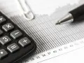 Calculadora y bolígrafo sobre gráficos. El modelo 309 para que sirve se puede deducir de estos elementos de contabilidad.