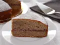 Una fetta di torta grano saraceno trentino, con marmellata e zucchero a velo, su un piatto bianco.