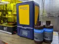 Dwa drukarki 3D Anycubic, w tym Anycubic Photon Mono SE, oraz butelki z żywicą do druku.