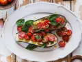 Melanzane ripiene vegetariane con pomodorini, basilico e semi di zucca, un piatto colorato e saporito.