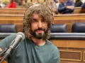 Mikel Izal, con su melena rizada y barba, sonríe ante el micrófono, listo para crear su propio paraíso musical en este escenario.