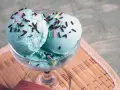 Ein Glas mit drei Kugeln blaues Eis, bestreut mit Schokostreuseln und bunten Zuckerstreuseln.