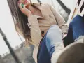 Kobieta w beżowym płaszczu z lumpeksu rozmawia przez telefon, siedząc na ławce. Jak wyczyścić płaszcz z lumpeksu?