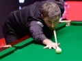 Ronnie O'Sullivan, jeden z najlepsi snookerzyści wszechczasów, skupiony przy zielonym suknie, celuje w bilę.