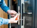 Mani che sostituiscono serratura porta con cacciavite.