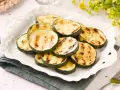 Rodajas de calabacín a la plancha, tiernas y con marcas de parrilla, servidas en un plato blanco.