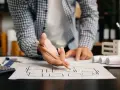 Architekt analizuje plany mieszkania, zastanawiając się, dlaczego od 2026 roku każde mieszkanie na sprzedaż musi mieć audyt akustyczny.