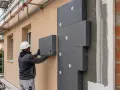 Operaio applica pannelli isolanti per il cappotto casa. Lavori di ristrutturazione in corso.