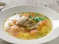 Aromatyczna zupa rybna, przepis babci, z kawałkami ryby, ziemniakami i marchewką, ozdobiona natką pietruszki.