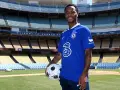 Raheem Sterling w niebieskiej koszulce Chelsea z piłką, na tle stadionu. Jego statystyki w klubie są obiecujące.