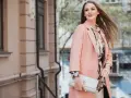 Donna con cappotto rosa e abito floreale, perfetta idea su come vestirsi per una comunione.