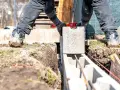 Budowniczy układa bloczek fundamentowy, sprawdzając poziom. Kluczowa jest odpowiednia zaprawa do bloczków fundamentowych, by konstrukcja była stabilna.