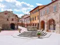 Piazza con pozzo antico e case in pietra e intonaco colorato, un assaggio di cosa vedere a Civitella in Val di Chiana.