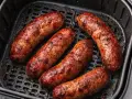 Salsiccia dorata e succulenta in friggitrice ad aria, pronta per essere gustata.