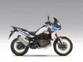 Nowy motocykl Honda Africa Twin 1100 w białym malowaniu z niebieskimi i czerwonymi akcentami, gotowy na przygodę.