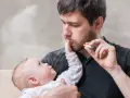 Mann raucht in der Wohnung, Baby im Arm. Rauchwolken umgeben sie. Ein besorgter Blick, der an das Jugendamt erinnert.