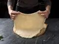 Rozciąganie elastycznego ciasta na pizzę, idealnego do szybkiego przepisu na ciasto do pizzy.