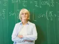Nauczycielka matematyki przed tablicą z równaniami. Zatrudnienie nauczyciela po 1 września do kiedy umowa?