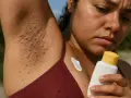 Axila con vellos incipientes y granitos. Una mujer mira con preocupación una crema, quizás pensando que si te depilas sale más pelo.