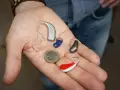 Różne aparaty słuchowe na dłoni. Pokazują, jak działa aparat słuchowy, wzmacniając dźwięki.