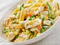 Penne z kurczakiem w kremowym sosie, z groszkiem, marchewką i fasolką szparagową. Pyszne danie obiadowe.