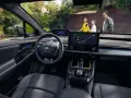 Wnętrze Toyoty bZ4X z ekranem nawigacji. Rodzina na zewnątrz, zastanawia się nad ceną i możliwościami tego elektrycznego SUV-a.